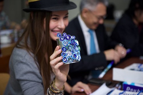 Denise Keller showing off her work of art with Mr. Thirawit Leetavorn in the background creating his craftwork.